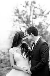 Happy newlywed couple hugging & smiling in park b&w