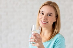 Portrait of happy smiling young woman with glass of fresh water. Healthy lifestyle concept