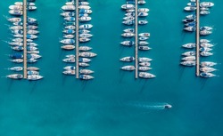 Aerial view of luxure yachts and motorboats moored in a port with clear blue water in summer. Top view from drone of sailboats and various speed boats in dock. Pula, Croatia