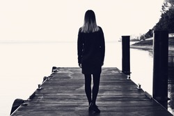Stylish girl on a seaside pier. Black and white photography, soft focus