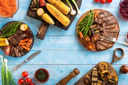 Grilled beef steak with grilled vegetables on wooden blue table with copy space, top view