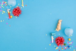 Colorful celebration pattern with various party confetti, balloons and red bows on blue background. Flat lay