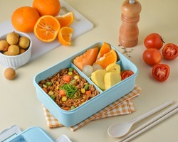 Prepare Children's School Supplies in the lunch box, with ingredients vegetables fried rice, tamagoyaki or omelet, orange, melon, and longan. 