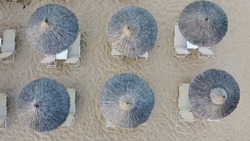 Aerial view of rows of cane umbrellas and sunbeds on a sandy Mediterranean beach