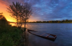 sunset over the river on the background of a submerged boat