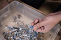 Man holding a screw for carpentry, furniture repair, repair and assembly of the house. Step 1: Pour all the screws or bolts into the box, close up, details when assembling furniture, storage box