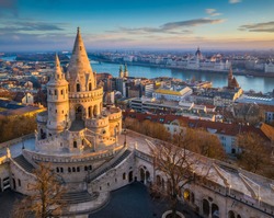 Budapest, Hungary - The main tower of the famous Fisherman's Bastion (Halaszbastya) from above with Parliament building and River Danube at background on a sunny morning