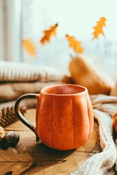Hot steaming Cup of tea with autumn leaves, pumpkins and spices on the windowsill. Autumn mood
