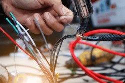 close up of a car audio technician's hand soldering wires