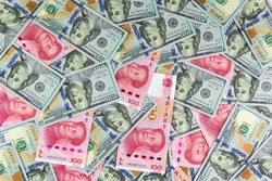Chinese Yuan bills vs U.S. dollar as background, a symbol of the relationship between China and the United States in economic and trade cooperation and confrontation.