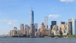 Panorama view of Manhattan, New York City with blue sky and slightly cloud. Battery park on the edge of the shore which surround by many tall building in business area.