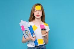 Boring young Asian woman holding document file with coffee cup and a sticky note on the face, stand on studio shot blue background.