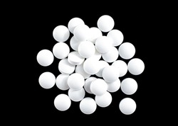 White round small pills on a black background, heap, top view, macro