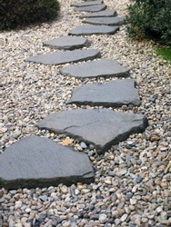 Path of plated stones on gravel bed in Japanese Garden. Meditative stone walkway. Garden architecture, pathway accessory to garden pond.