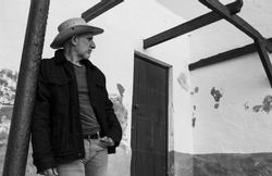 Portrait of adult man in cowboy hat and jeans against wall with light and shadow. Almeria, Spain