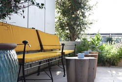 Beautiful terrace of the restaurant with ocher and blue shades of objects. Two yellow benches with wooden tables with white ashtrays. Fantastic combination of restaurant interior colors. 
