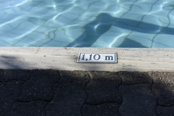 A sign indicating that the pool is 5 feet deep. Pool tile with a sign for pool depth. A symbol for measuring the depth of water in the pool. 