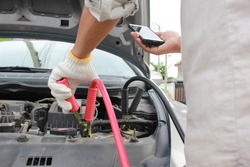 Close-Up Of Charging automobile discharged battery and Man calling to car mechanic service