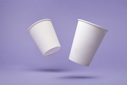 White paper cup of coffee colored background.  Flying paper cup on violet background. Isolated for mock up