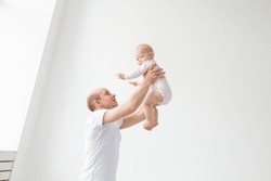 Happy young father lifting cute baby up high in air, spending and enjoying time together with daughter