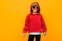 Stylish young boy in red sweatshirt and white t-shirt puts hands on his chest