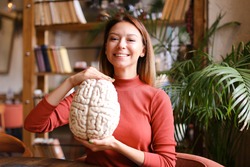 Female smiling caucasian psychologist holding human brain model at cabinet. Concept of anatomy and psychiatry.
