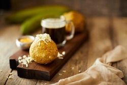 Ecuadorian bolon de verde or green plantain dumplings stuffed with cheese and accompanied by a traditional coffee. On a wooden background.