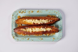 Ecuadorian maduro con queso consists of baked ripe plantains stuffed with cheese. It’s on a white background. 