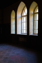 View of three neo-gothic windows with beautiful wooden frames in the interior of a dark room in Sharovsky castle, Ukraine.