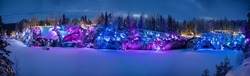Night winter view with multi-colored illumination on the old abandoned quarry park Ruskeala. Panorama.