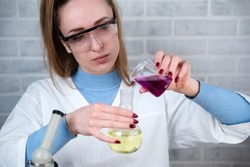 The laboratory assistant mixes two substances in a flask. Conducting chemical experiments. Scientific laboratory.