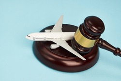 Aviation law concept. Judge gavel and airplane on blue background. Flight cancellation