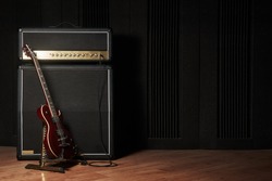 Red electric guitar and classic amplifier on a dark background                        