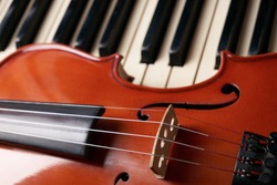 Classical musical stringed instrument violin on piano keys.  Fiddle on piano keyboard.