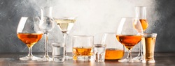 Set of hard strong alcoholic drinks and spirits in glasses in assortment: vodka, cognac, tequila, brandy and whiskey, grappa, liqueur, vermouth, tincture, rum. Gray bar counter 