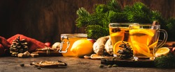 Healing black winter tea with ginger, honey, lemon. Immune booster drink in glass cup on rustic wooden table background with copy space