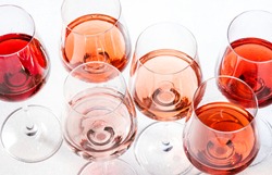 Rose wine glasses set on wine tasting. Degustation different varieties, colors and shades of pink wine concept. White background, top view