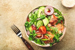 Fresh salad with grilled chicken, cherry tomatoes, arugula, red onion, avocado, sesame seeds and lemon oil dressing. Healthy food concept. Top view. Copy space