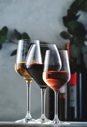 Wines assortment. Red, white, rose wine in wineglasses and bottles on gray background. Wine bar, shop, tasting concept