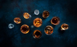 Strong alcohol drinks, hard liquors, spirits and distillates iset in glasses: cognac, scotch, whiskey and other. Blue background, top view 