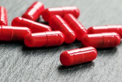 Red pills in capsules of anemia on a black table, selective focus, macro shot, shallow depth of field