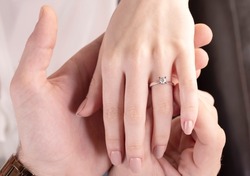 Beautiful lady hand. The background is white and a diamond ring on your finger.