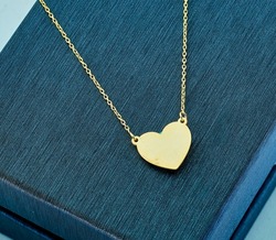 Gold jewelry. Heart necklace on background