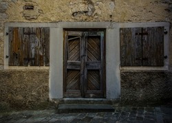 An old wooden door and windows in an historic derelict residential building in the medieval village of Buzet in Istria, western Croatia 