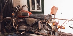 
Old rusty motorcycle of the Soviet Union. Abandoned vehicles under a street canopy. Moto covered with rust, a model for the restoration of an old transport