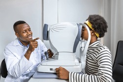 African young woman girl doing eye test checking examination using autorefractor in clinic or optical shop. Eyecare concept.