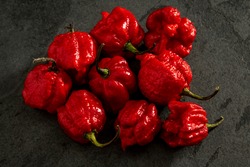 Habanero peppers on dark background, ripe red on rustic table, hot spicy habanero peppers