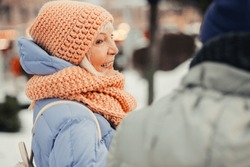 Close up of an elderly woman in winter clothes looking happy and smiling to her friend