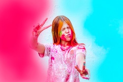 happy girl painted with Holi festival pink and blue colours on white wall background