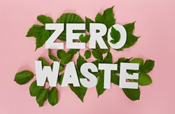 zero waste paper text witj green leaves on pink background 